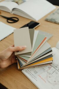 A person examining paint swatches on a wall in a sunlit living room, comparing matte and glossy finishes.