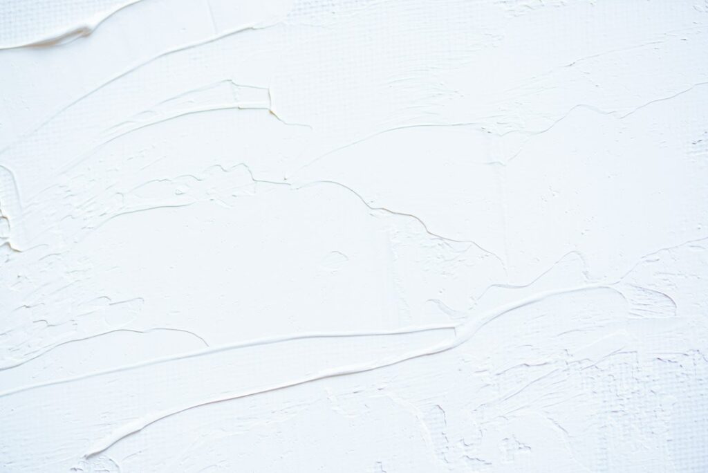 Paint samples beside a wall showing flat, eggshell, and satin finishes under natural light.
