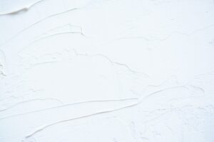 Paint samples beside a wall showing flat, eggshell, and satin finishes under natural light.