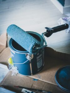 Homeowner sorts labeled paint cans into a sturdy box beside absorbent packing material.